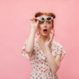 驚いてサングラスを持ち上げている女性