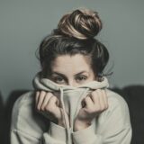 フーディーで口元を覆う女性