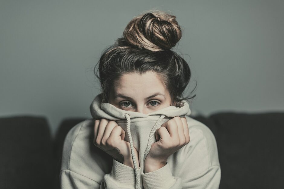 フーディーで口元を覆う女性